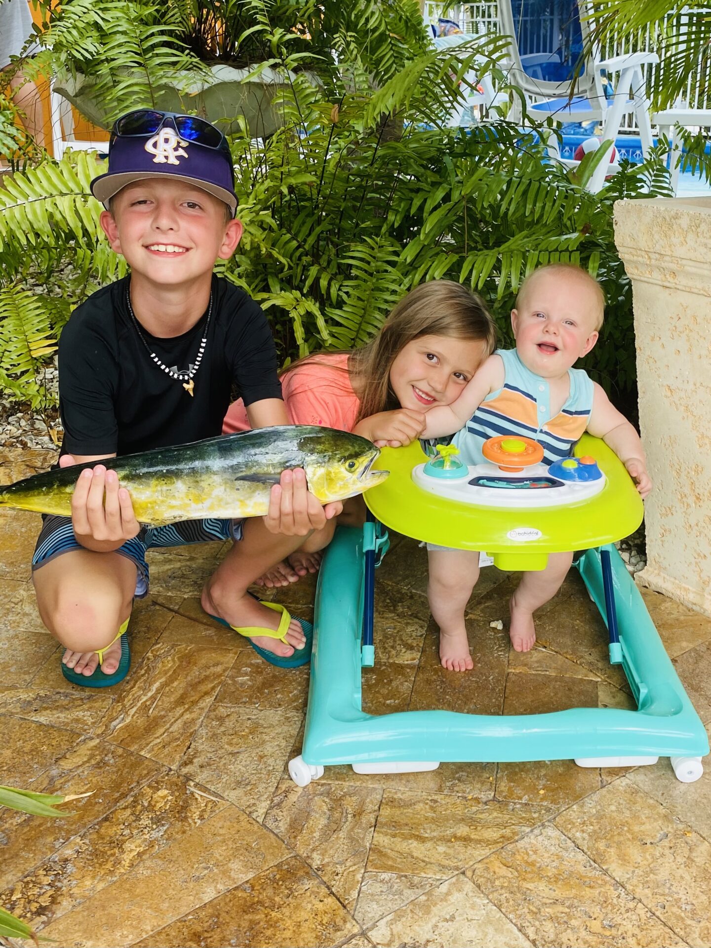 A boy holding a fish with two children